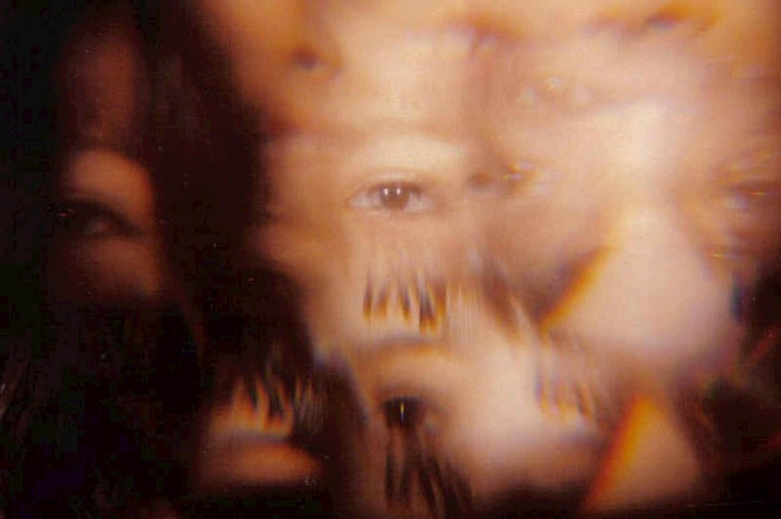 Abstract image featuring defocused faces and eyes, creating a surreal artistic effect.
